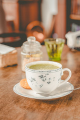 green tea matcha soy latte in a china cup with brown sugar and a glass of water on the side