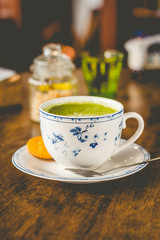 green tea matcha soy latte in a china cup with brown sugar and a glass of water on the side