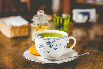 green tea matcha soy latte in a china cup with brown sugar and a glass of water on the side