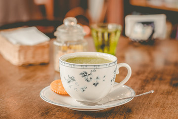 green tea matcha soy latte in a china cup with brown sugar and a glass of water on the side