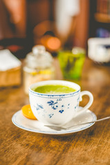 Fototapeta na wymiar green tea matcha soy latte in a china cup with brown sugar and a glass of water on the side
