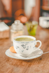 green tea matcha soy latte in a china cup with brown sugar and a glass of water on the side