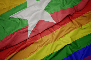 waving colorful gay rainbow flag and national flag of myanmar.
