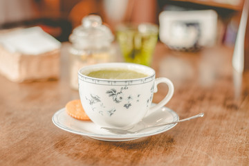 green tea matcha soy latte in a china cup with brown sugar and a glass of water on the side