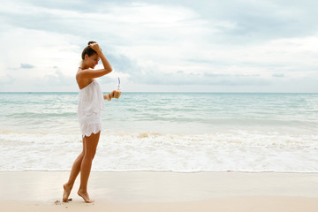 Fototapeta na wymiar Beautiful woman wearing white jumpsuit walk on the beach