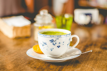 green tea matcha soy latte in a china cup with brown sugar and a glass of water on the side