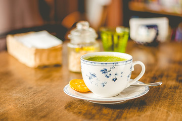 green tea matcha soy latte in a china cup with brown sugar and a glass of water on the side