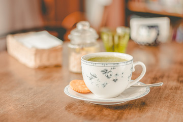 green tea matcha soy latte in a china cup with brown sugar and a glass of water on the side