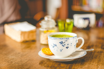 green tea matcha soy latte in a china cup with brown sugar and a glass of water on the side