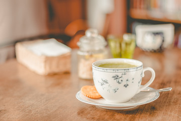 green tea matcha soy latte in a china cup with brown sugar and a glass of water on the side