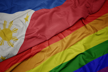 waving colorful gay rainbow flag and national flag of philippines.