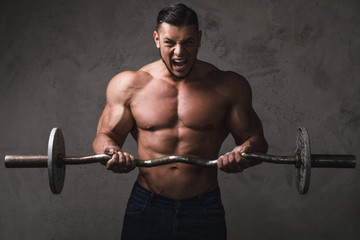 Massive brutal bodybuilder doing exercises with barbell