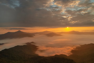 Mountain view morning of top hill around with sea of mist in valley with orange sun light and cloudy sky background, sunrise at Pha Tang, Chiang Rai, northern of Thailand.