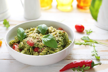 Pasta with spinach and tomatoes. A dish on a white wooden table