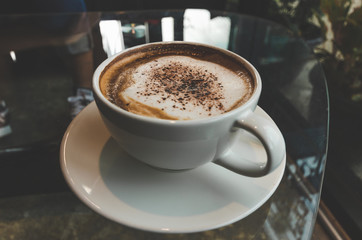 close up modern hot black coffee the cappuccino on dark background with coffee bubble foam pattern and texture in black cup looking and feel so delicious on glasses table in coffee shop.