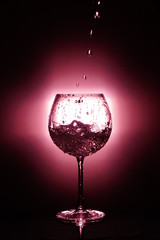 Pouring water into glass , black background and red light