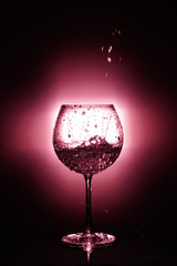 Pouring water into glass , black background and red light