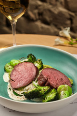 Gourmet roasted meat with broccoli and zucchini seasoned with sauce.