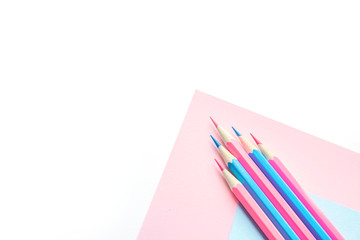 Pink and blue pencils and paper on white background. Top view, flat lay composition, frame, layout. Copy space for text or design.
