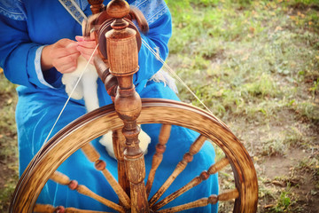 Distaff creates a thread from a spindle. Hand spinning wheel in nature, close-up.