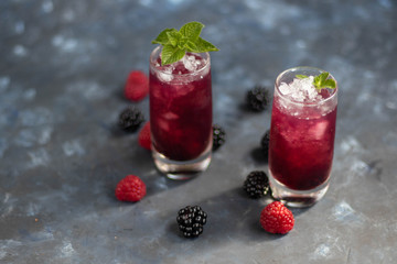 Tincture of vodka and blackberry of homemade production. Glasses are filled with crushed ice and decorated with mint tones.