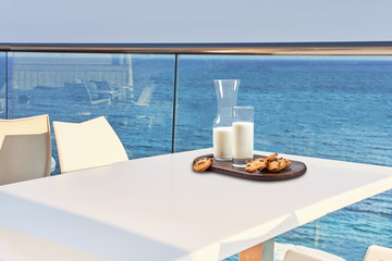 Table for two served with a breakfast on outdoor hotel balcony with a sea view.