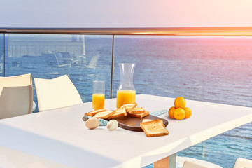 Table for two served with a breakfast on outdoor hotel balcony with a sea view.