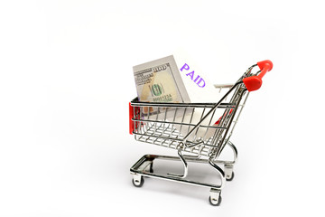 Shopping cart with one hundred US dollar bills isolated on white background.