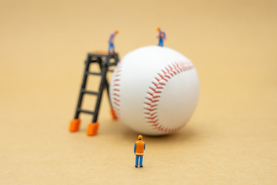 Miniature people Construction worker with baseball on Abstract background and red stitching baseball. White baseball with red thread.Baseball is a national sport of Japan. It is popular.