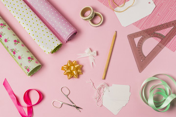 High angle view of stationery supplies with gift wrap and tags on pink background