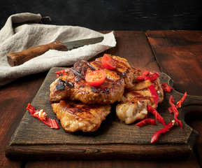 grilled pork pieces of meat on a grill lie on a vintage wooden board