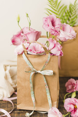 Brown paper bag with fresh pink eustoma flower on wooden table