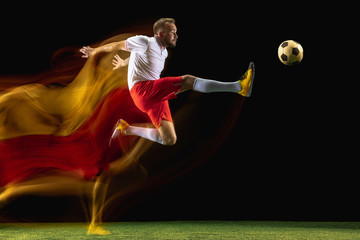 Flying. Young caucasian male football or soccer player in sportwear and boots kicking ball for the...