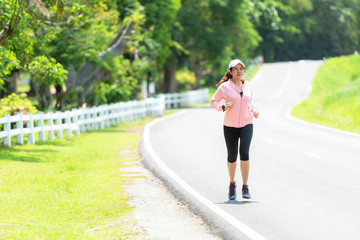 Sporty asian woman runner running and jogging through the road.  Outdoor Workout in a Park. Weight Loss and Healthy Concept