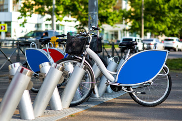 Obraz premium bike rental in a city park on the background of the road with traffic jam, rental bike gray with blue advertising space.