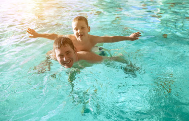 Happy father and son swimming lesson in the pool. Child learning