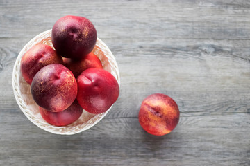 Ripe organic nectarines in white basket on  gray background.