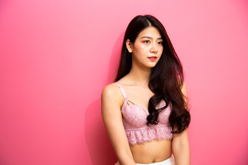 Beautiful young asian girl wearing sexy luxury stylish pink lingerie relaxing sitting on pink background. asian woman smiling and very happy