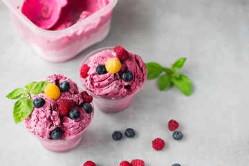 Homemade ice cream or sorbet made from fresh berries with basil in glass bowl on a gray background.