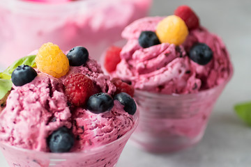 Homemade ice cream or sorbet made from fresh berries with basil in glass bowl on a gray background.