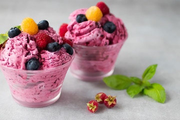 Homemade ice cream or sorbet made from fresh berries with basil in glass bowl on a gray background.