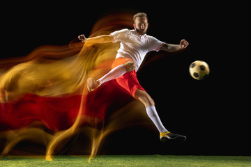 Confident. Young caucasian male football or soccer player in sportwear and boots kicking ball for...