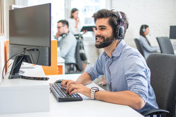 Young handsome man wearing headset working on computer in call center