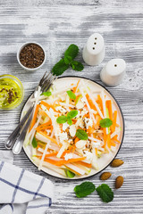 Turnip, apple carrot salad on rustic wooden background. Top view, space for text.