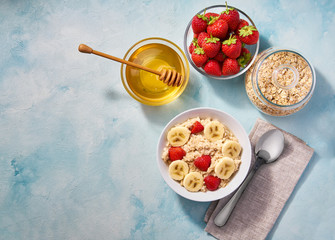 Homemade oatmeal with banana and strawberry for breakfast on a turquoise background. Top view. Healthy eating, healthy breakfast food.