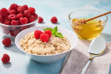 Homemade oatmeal with  fresh raspberries for breakfast on a turquoise background. Healthy eating, healthy breakfast food