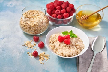 Homemade oatmeal with  fresh raspberries for breakfast on a turquoise background. Top view.