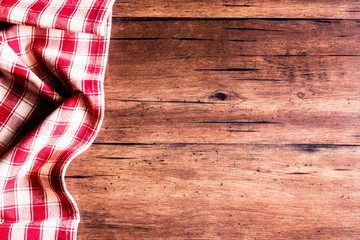 Checkered red napkin on an old wooden brown background, top view. Image with copy space. Kitchen table with a towel - top view with copy space. 