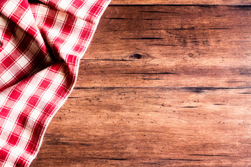 Checkered red napkin on an old wooden brown background, top view. Image with copy space. Kitchen table with a towel - top view with copy space. 