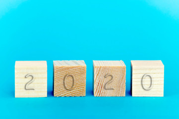 2020 on wooden cubes on blue background close-up top front view, new year concept